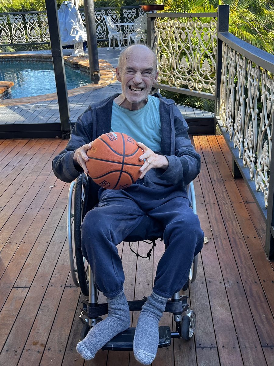 Derek smiling outside with a basketball