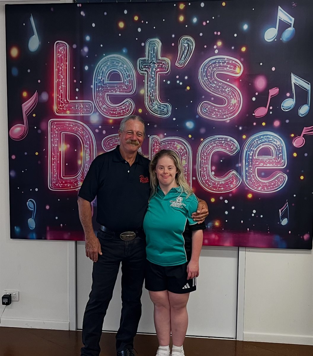 Two people in front of a Let's Dance backdrop