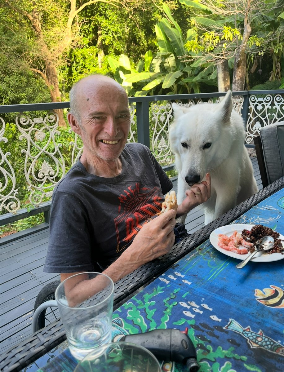 Sharing a snack at an outdoor table with one of the dogs