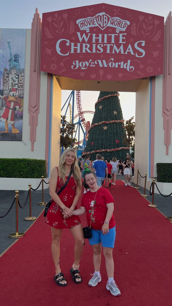 Two people at a theme park entrance decorated for Christmas